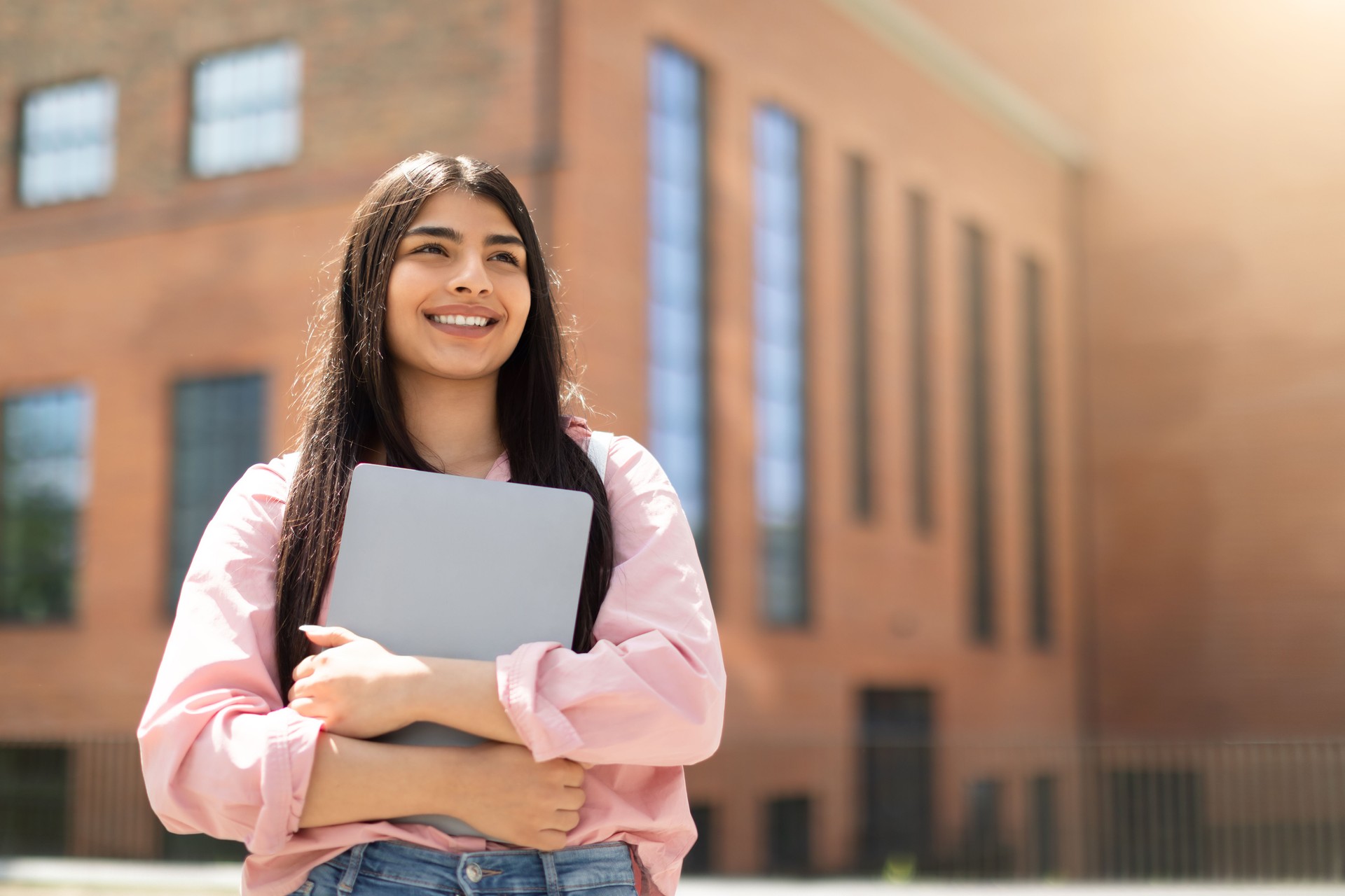 Young girl holding laptop and looking up